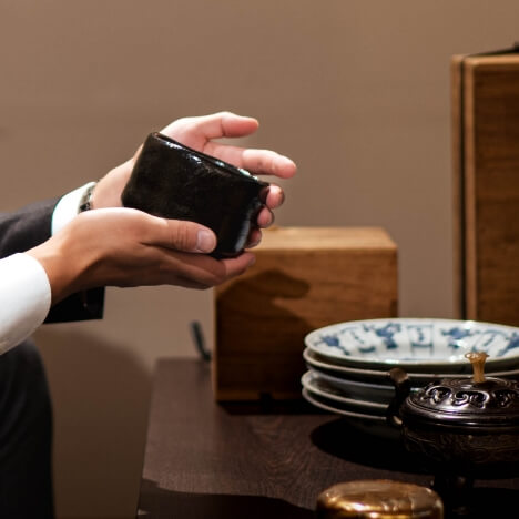 黒い器を手に取る男性