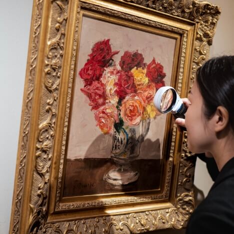 ルーペで薔薇の絵画を見る鑑定士